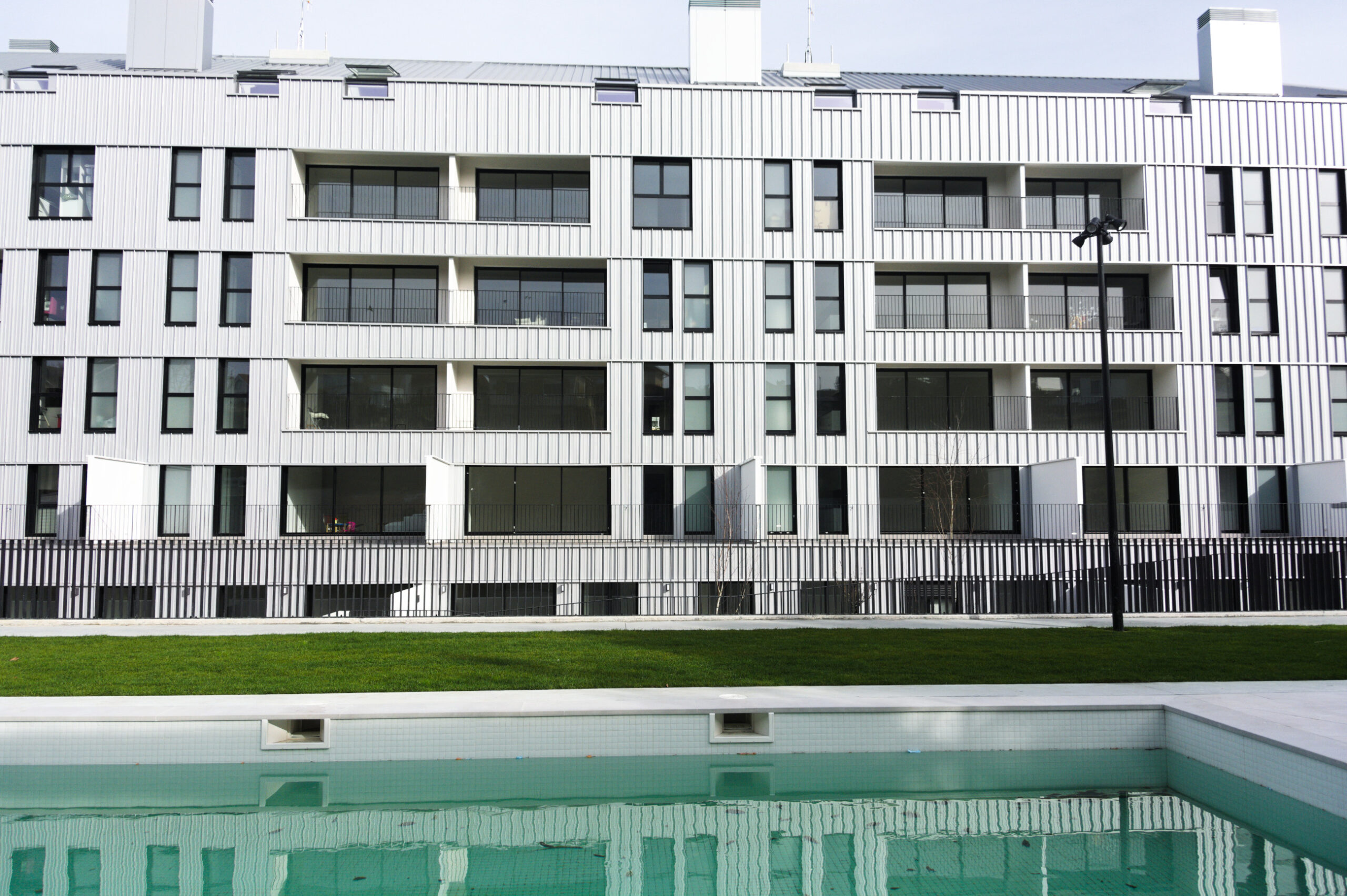 Fachada de un edificio desde una zona con piscina y jardín