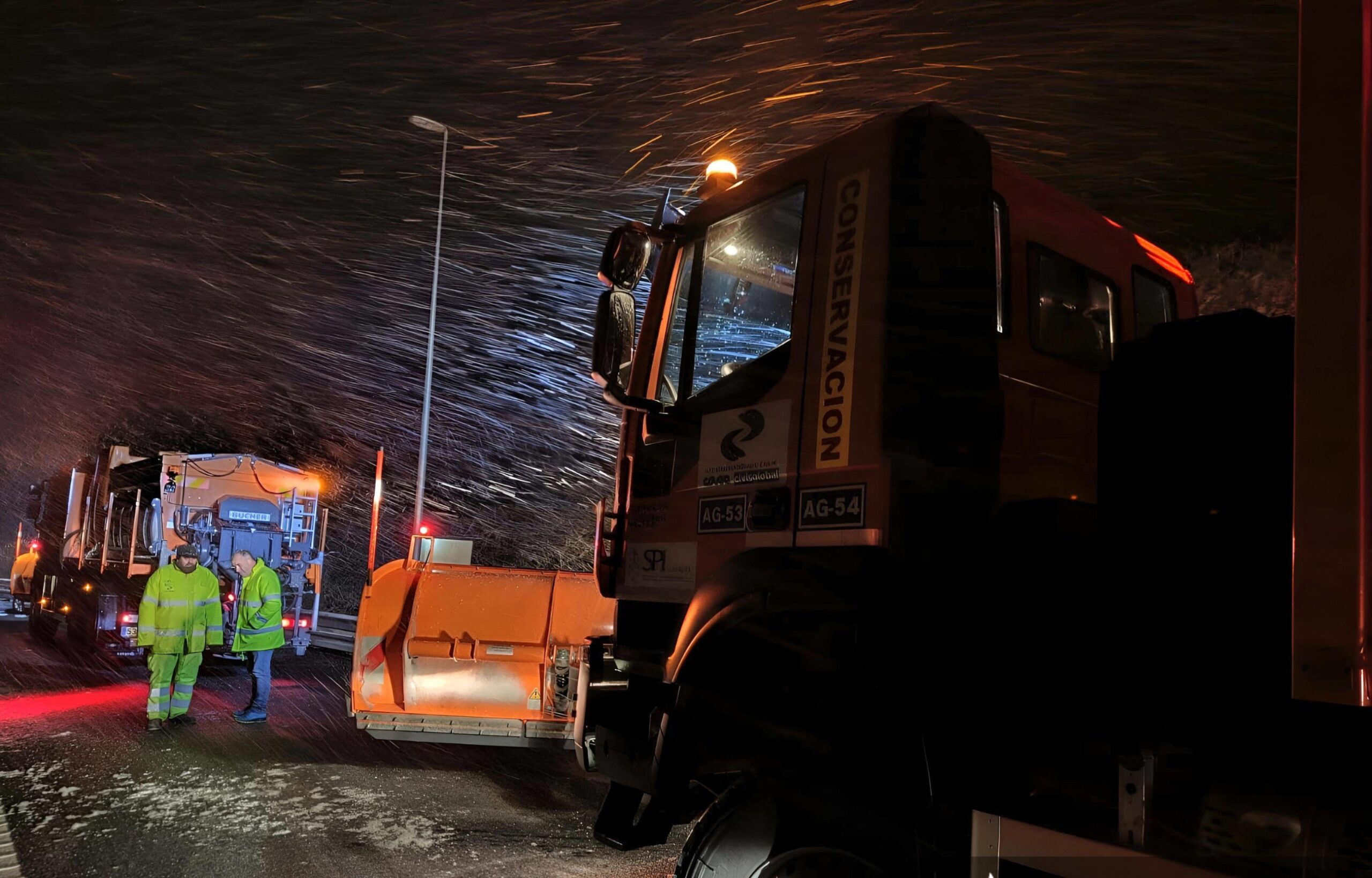 maquinaria y personal de trabajo en carreteras en una noche de nevada