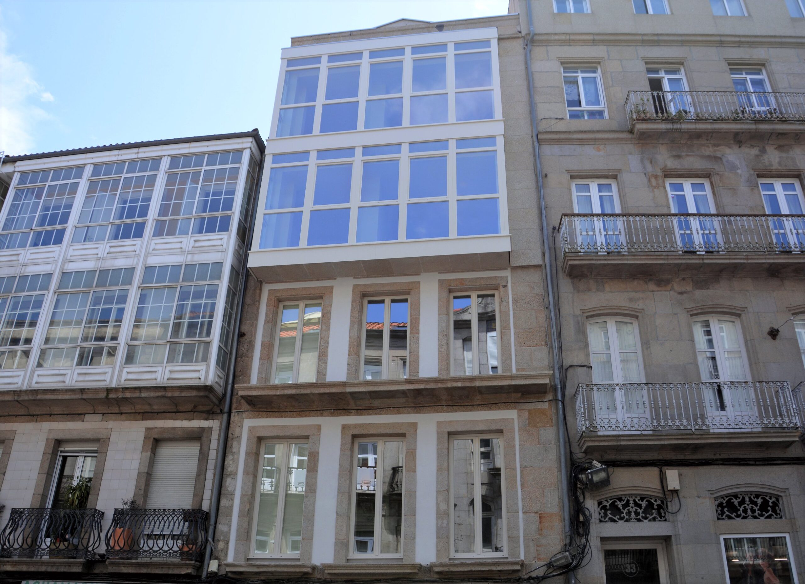 fachada de un edificio de estilo antiguo realizado en piedra y con ventanas el dos pisos y una galería en otros dos
