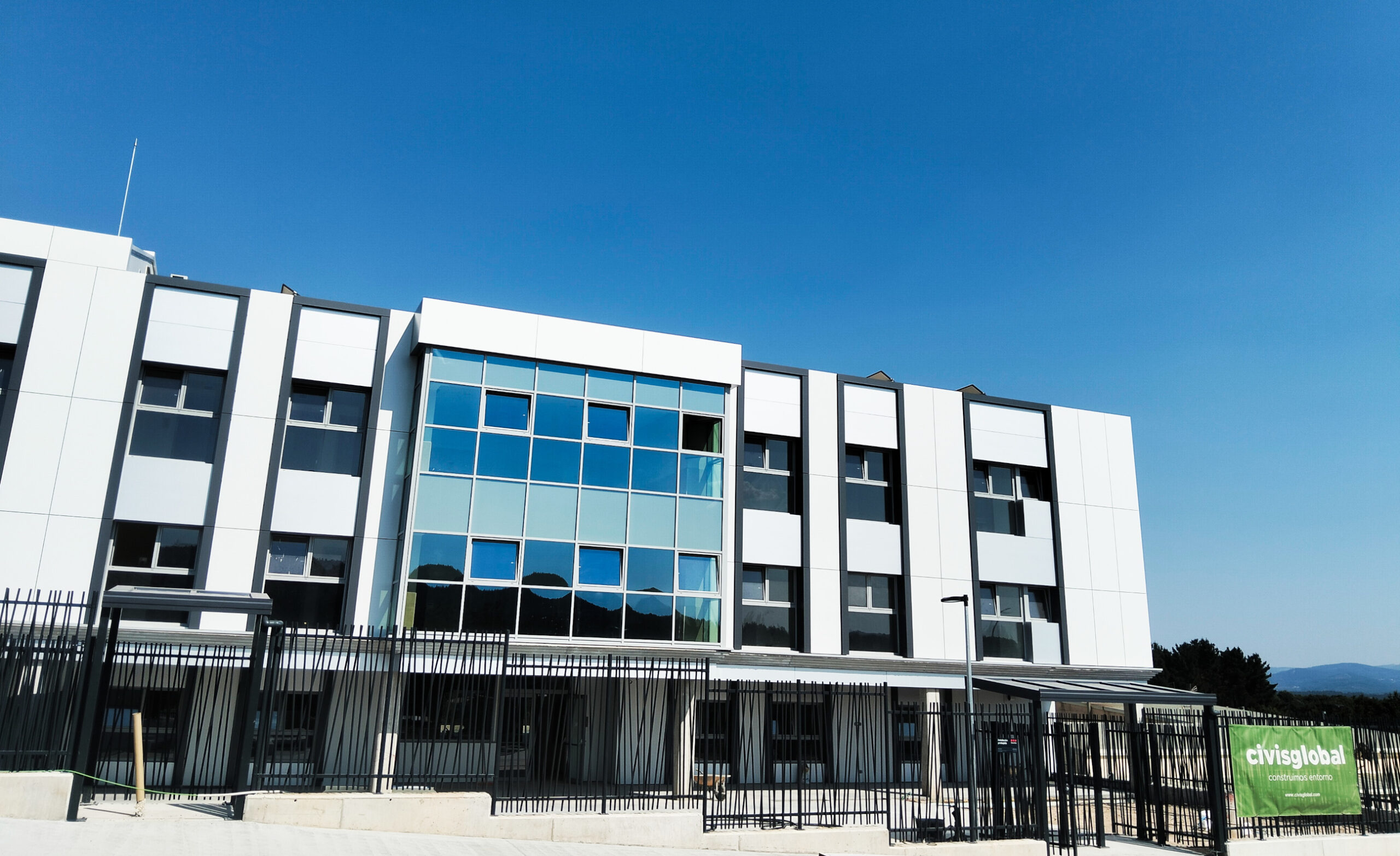 fachada de edificio con color blanco y portal de entrada flanqueado con verja oscura